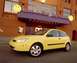 2002 Ford Focus - A yellow 2002 Ford Focus is parked in front of a building with a sign that says "Have a Nice Day Cafe".