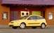 2002 Ford Focus - A yellow 2002 Ford Focus hatchback is parked on the street in front of a building with colorful doors.