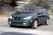 2002 Ford Focus - A green 2002 Ford Focus hatchback is captured in motion on a paved road.