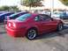 2002 Ford Mustang - A red Ford Mustang is parked in a lot with other vehicles visible in the background.