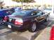 2002 Ford Mustang - A black Ford Mustang is parked in a lot with other vehicles around it.