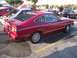 2002 Ford Mustang - A red 1974 Ford Mustang II coupe is parked next to other vehicles, with its rear window distinctive louvers.