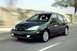 2002 Ford Focus - A dark green Ford Focus hatchback is captured in motion on a paved road, with a blurred background.