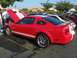 2002 Ford Mustang - A red Ford Mustang Shelby GT500 is parked with its hood and trunk open, showing off its engine and rear spoiler.