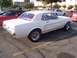 2002 Ford Mustang - A white 1967 Ford Mustang coupe with a red interior and side stripe is parked in a lot next to other vehicles.