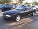 2002 Ford Mustang - A black convertible Mustang with a hood bra is parked in a lot with other vehicles.