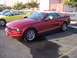2002 Ford Mustang - A red convertible Mustang is parked next to a yellow convertible Mustang.