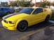2002 Ford Mustang - Yellow 2005 Ford Mustang GT with racing stripes, parked next to a blue Mustang.