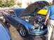 2002 Ford Mustang - A blue Ford Mustang is parked with its hood open, revealing the engine bay. Another car is visible in the background.