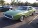 2002 Ford Mustang - A classic green Ford Mustang coupe is parked in a lot next to a convertible.