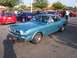 2002 Ford Mustang - A classic teal 1965 Ford Mustang coupe is parked in a lot with other vehicles.