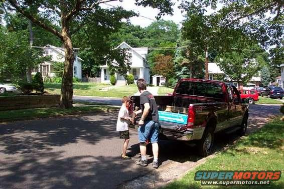 guy and kid loading stuff into back of red pickup truck