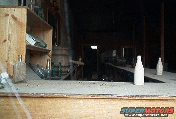 Interior of an old-fashioned bar with shelves stocked with bottles and a wooden barrel