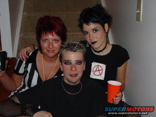 Three people in Halloween costumes with dark makeup and punk-inspired clothing