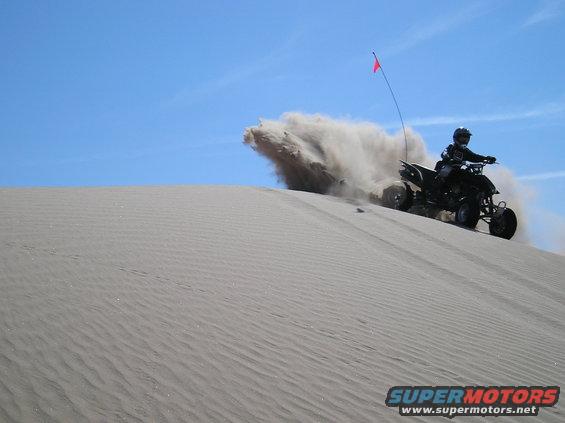Quad bike kicking up sand on a dune
