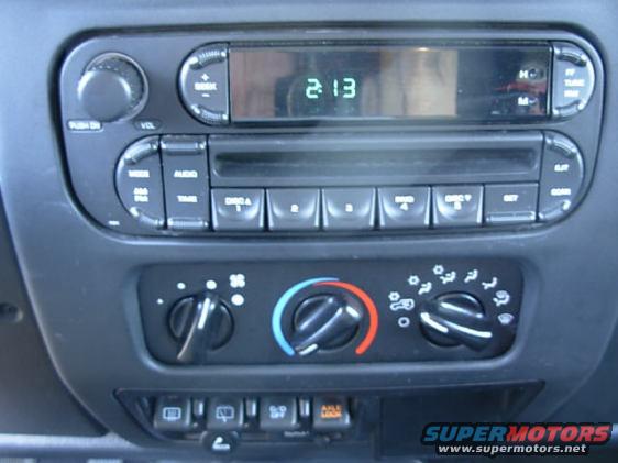 Car interior dashboard with radio and climate controls. Digital clock shows 2:13
