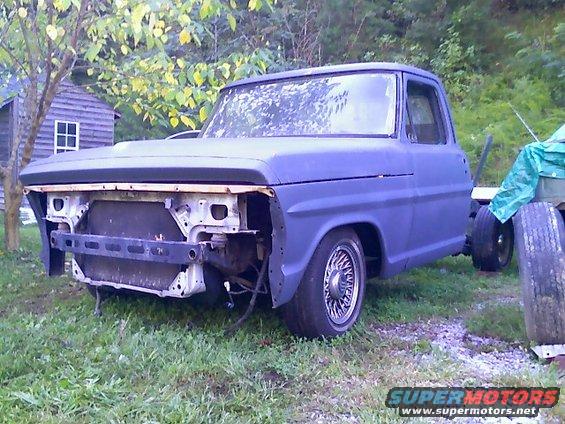 Blue pickup truck front view, missing grille and bumper
