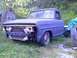 2002 Ford Crown Victoria - A blue pickup truck sits in a grassy yard, missing its front grille and bumper.