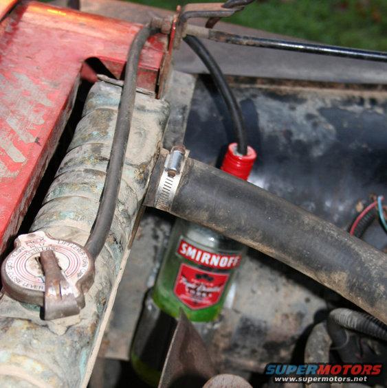 engine bay with radiator cap and a Smirnoff bottle used as a coolant reservoir