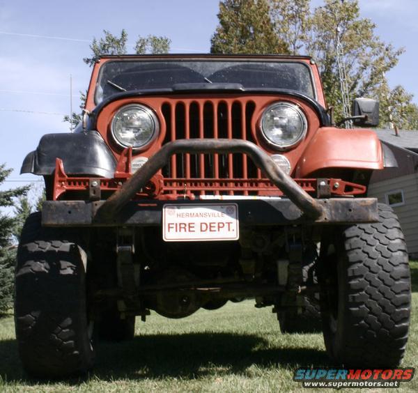 Orange Jeep CJ5 with a "FIRE DEPT." license plate, front view, on grass