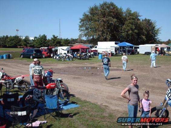 Outdoor event with motorcycles, people, tents, and vehicles under a clear blue sky. Date stamp reads 02/20/2005