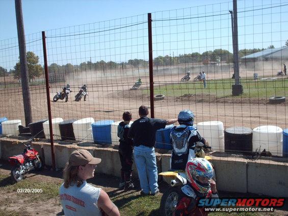 Dirt track race with multiple motorcycles and spectators watching