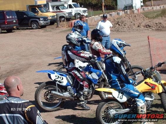 Motocross riders in gear on dirt bikes, some with numbers 22 and 13