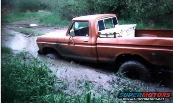 Orange pickup truck stuck in mud, side view