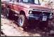 1976 Ford F-100 - This red Ford F-100 navigates a rough, off-road terrain with its front end angled towards the viewer.