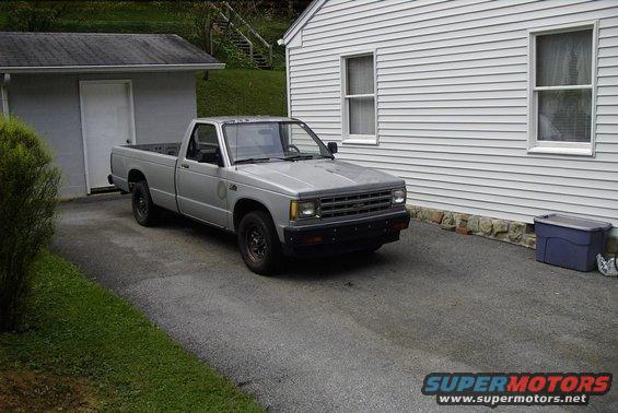 Silver pickup truck parked in driveway, front 3/4 view. Black grille and bumper, black wheels