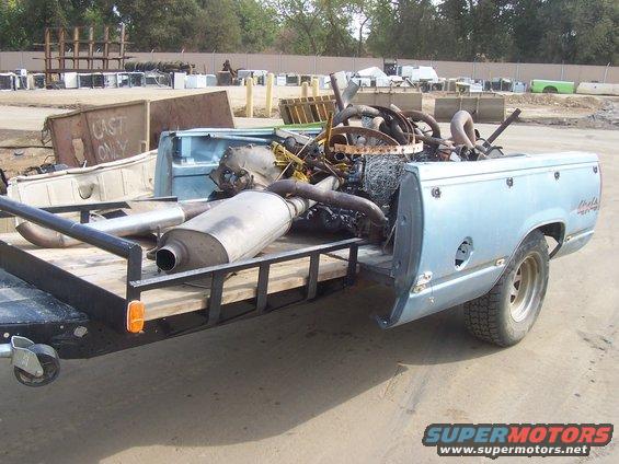 Light blue pickup truck bed loaded with scrap metal and engine parts. Badge reads 'Cheyenne'