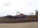 1994 Ford F-150 - A junkyard scene a large pile of scrap metal and heavy machinery under a cloudy sky.
