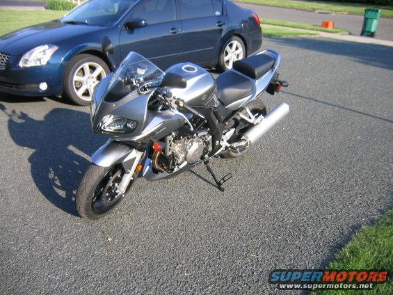 Silver 2006 Suzuki SV1000S motorcycle parked next to a blue sedan