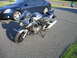2006 Suzuki SV1000S - A silver 2006 Suzuki SV1000S motorcycle is parked on an asphalt driveway next to a blue sedan.
