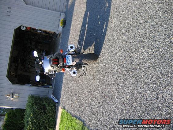 Rear view of a 2006 Suzuki SV1000S parked in a driveway next to an open garage