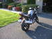 2006 Suzuki SV1000S - A silver 2006 Suzuki SV1000S motorcycle is parked on an asphalt driveway in front of a garage.
