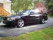 2003 Mercury Marauder - A black 2003 Mercury Marauder is seen from a three-quarter front view, parked on a paved surface in front of a residential house.