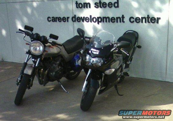 Two motorcycles parked outside a building; a black sportbike and a silver naked bike