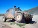 1969 Volkswagen Beetle - A modified 1969 Volkswagen Beetle with off-road tires and camouflage paint sits on rocks under a clear blue sky.