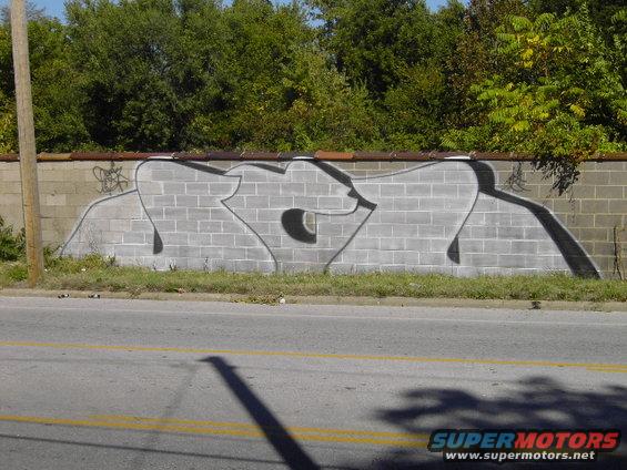 Graffiti art covers a cinder block wall next to a road