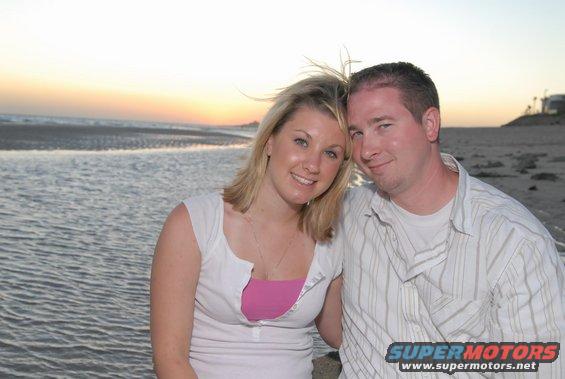 Couple posing on a beach with ocean and sunset in background