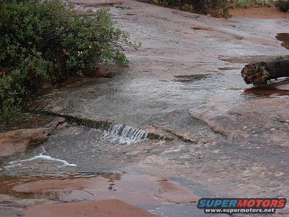 Water flowing over rocks with a log on the right