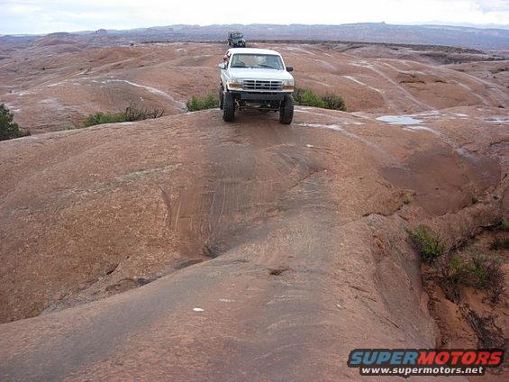 White 1992 Ford F-150 driving on a red rock trail with another SUV behind it