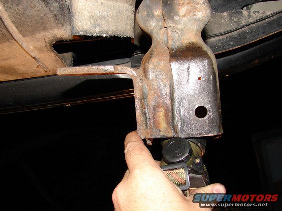 Rusty tow hook bracket being held by a hand with a tool