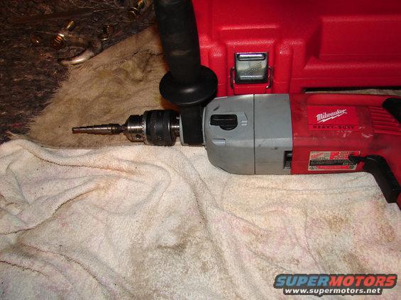 Red Milwaukee Heavy Duty drill with step bit on white towel