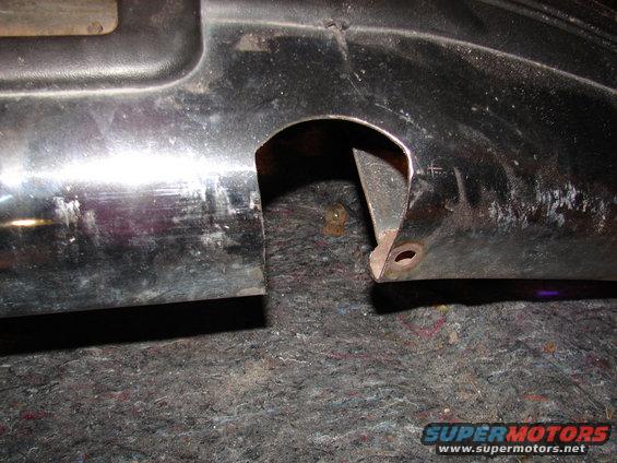 Close-up of a black plastic automotive part with a cut-out and mounting holes
