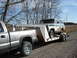 1979 Ford Bronco - A 1978 Ford Bronco is transported on a trailer behind a pickup truck on a gravel road.