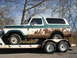 1979 Ford Bronco - This weathered Ford Bronco is being transported on a trailer under a clear sky.
