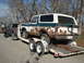 1979 Ford Bronco - A heavily rusted 1978 Ford Bronco is loaded onto a trailer behind a pickup truck.
