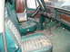 1979 Ford Bronco - The interior of a vintage truck shows faded green upholstery and a wood-grain dashboard.